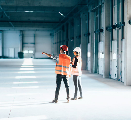 A man and a woman in hard hats doing a facilities maintenance check