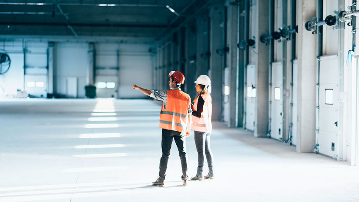 A man and a woman in hard hats doing a facilities maintenance check