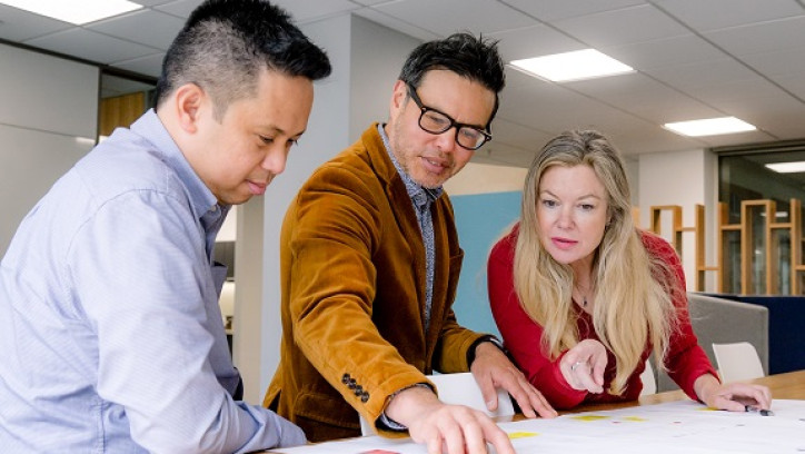 3 people looking at building design plans.