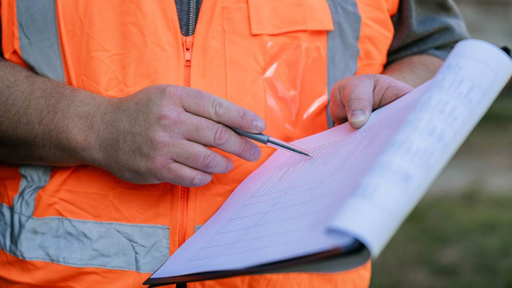 Man writing in document on clipboard