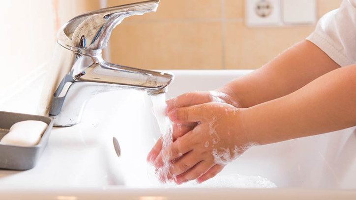 Child washing hands in bathroom sink