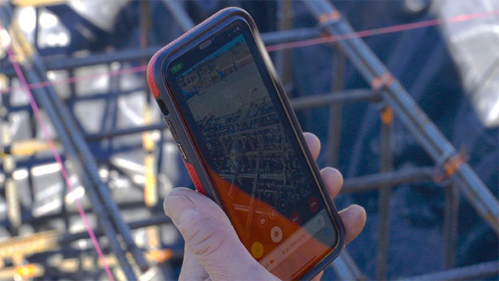 Cellphone held up in front of construction scaffold